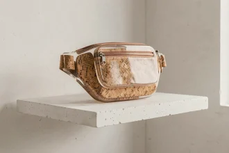 Sac banane futuriste en résine bio-sourcée et liège tressé posé sur une étagère en béton blanc dans un studio de design contemporain